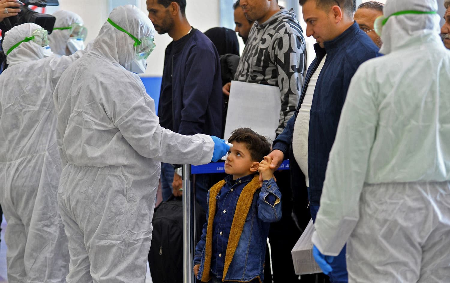 The body temperature of an Iraqi child returning from Iran is measured upon her arrival at the Najaf International Airport on February 21, 2020, after Iran announced cases of coronavirus infections in the Islamic republic. Photo via Haidar Hamdani / AFP