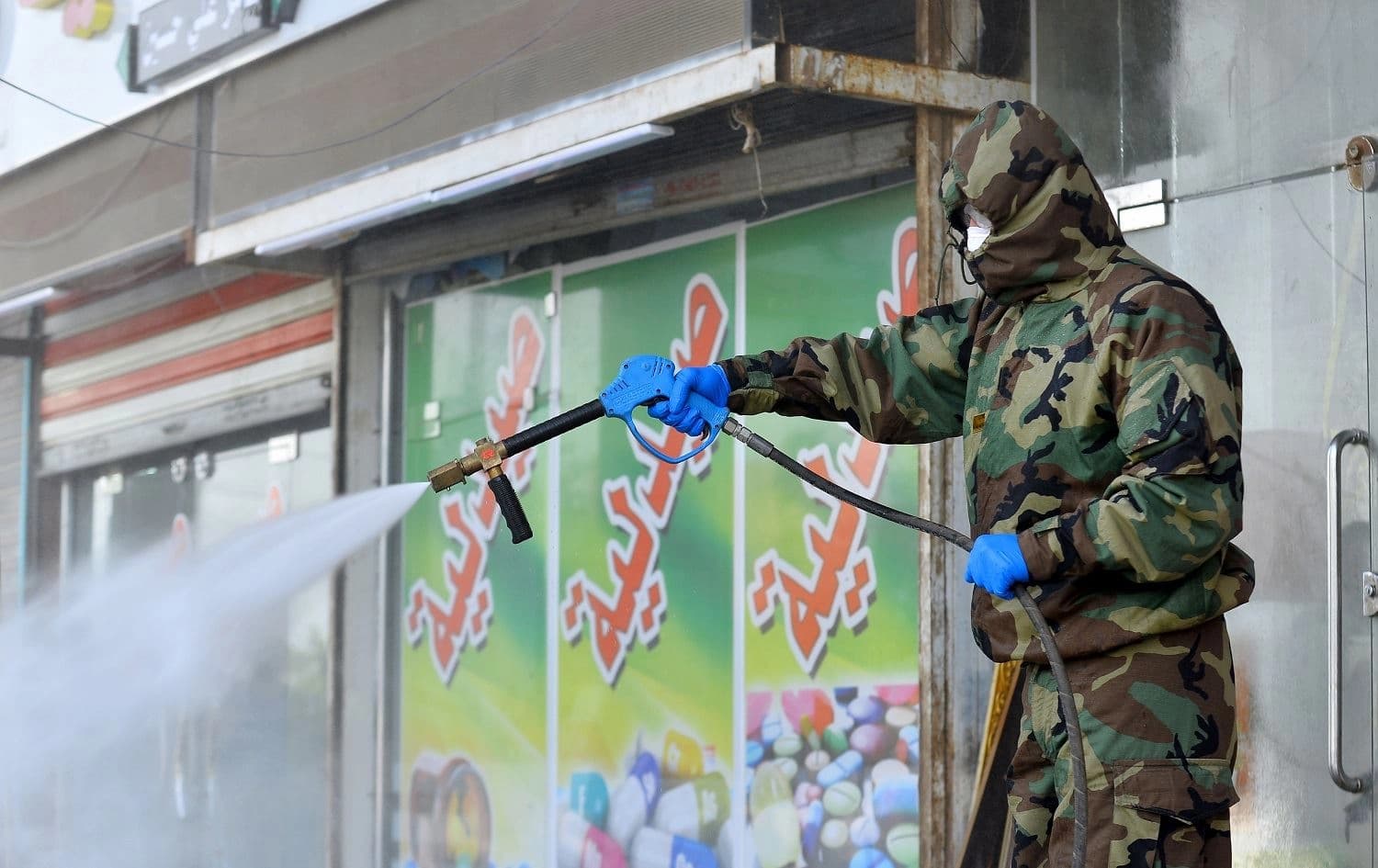 A member of the Iraqi civil defense sprays disinfectant around a building where Islamic students are quarantined in the central holy city of Najaf on February 26, 2020. Photo: Haidar Hamdani/AFP