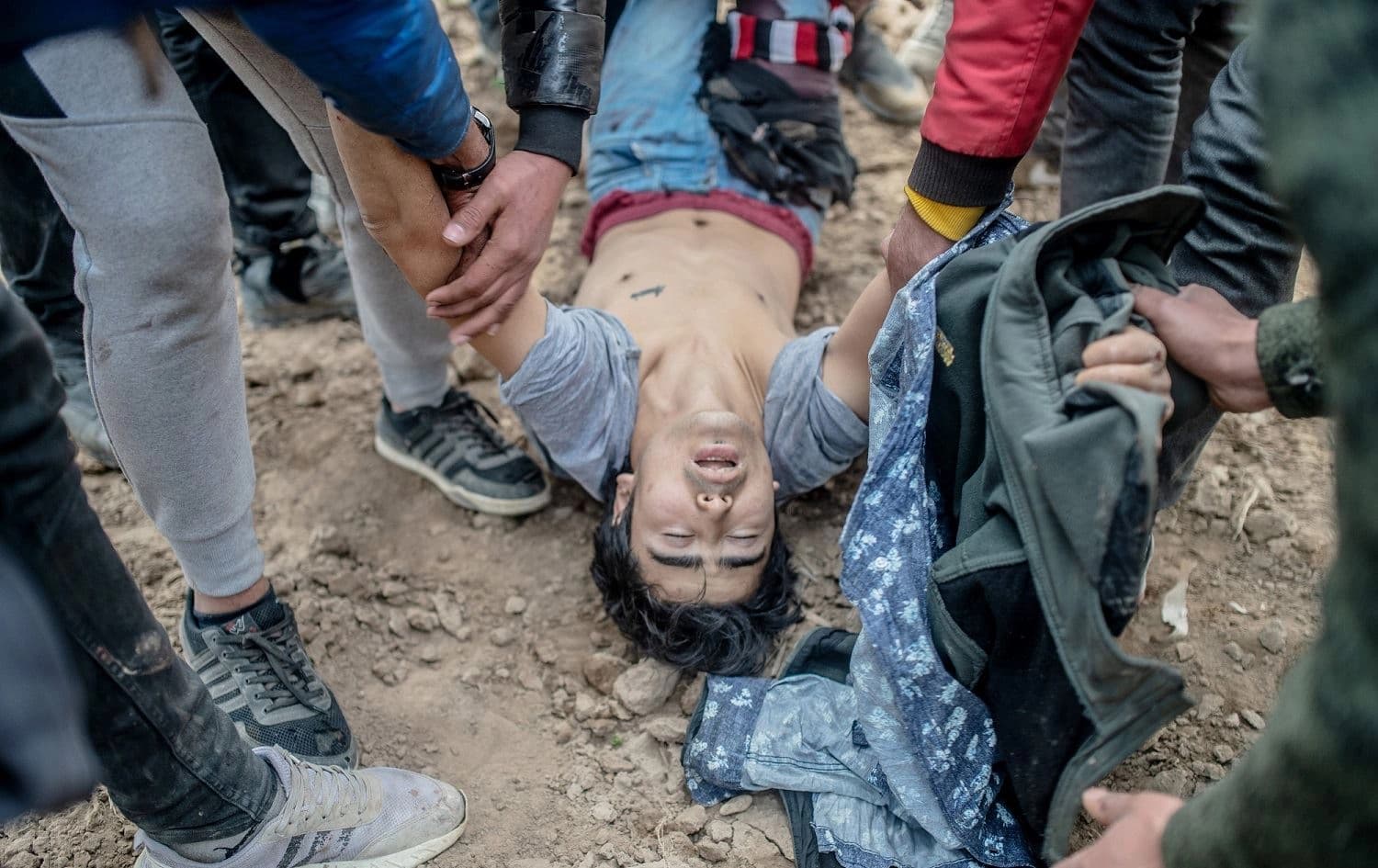 Migrants carry an injured man after Greek security officer shot him as they tried to pass on Greek side, near Pazarkule crossing gate in Edirne, Turkey, March 4, 2020. Photo: Bulent Kilic / AFP