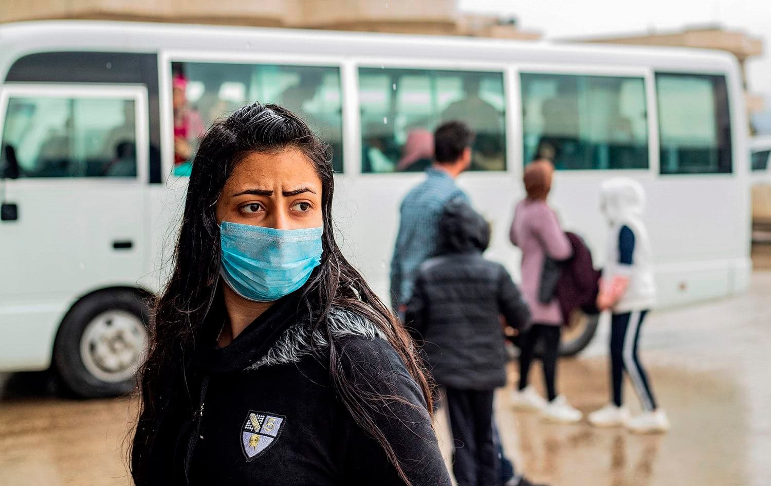 A mask-clad passenger looks on upon her arrival by bus in Syria’s Kurdish area from Iraqi Kurdistan via the Semalka border crossing in northeastern Syria, March 1, 2020. Photo: Delil Souleiman / AFP