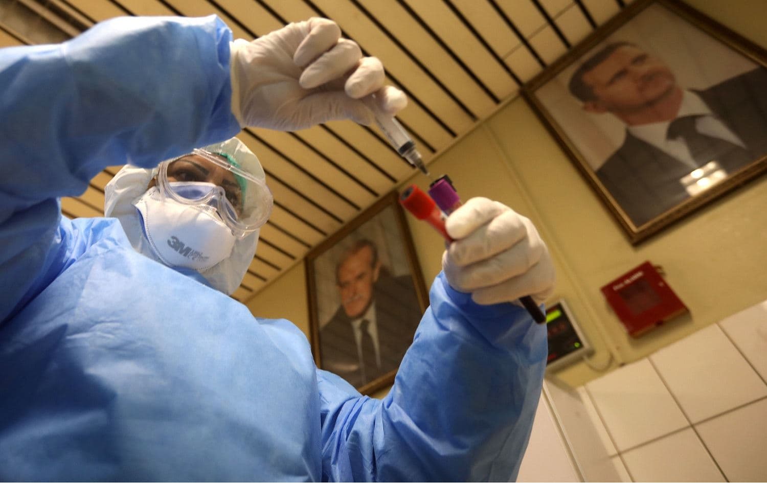A member of the sanitary section of al-Assad University Hospital runs blood tests at the special department designated for the novel coronavirus, Damascus, April 15, 2020. Photo: Louai Beshara / AFP