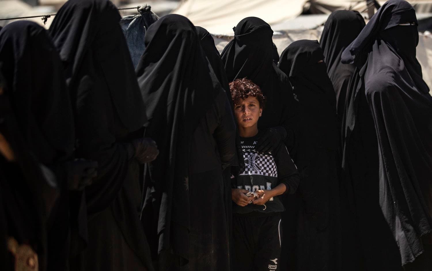 A boy looks on as he stands in line with women to receive aid at al-Hol camp in in the Hasaka province of northeast Syria on August 18, 2020. Photo: Delil Souleiman / AFP