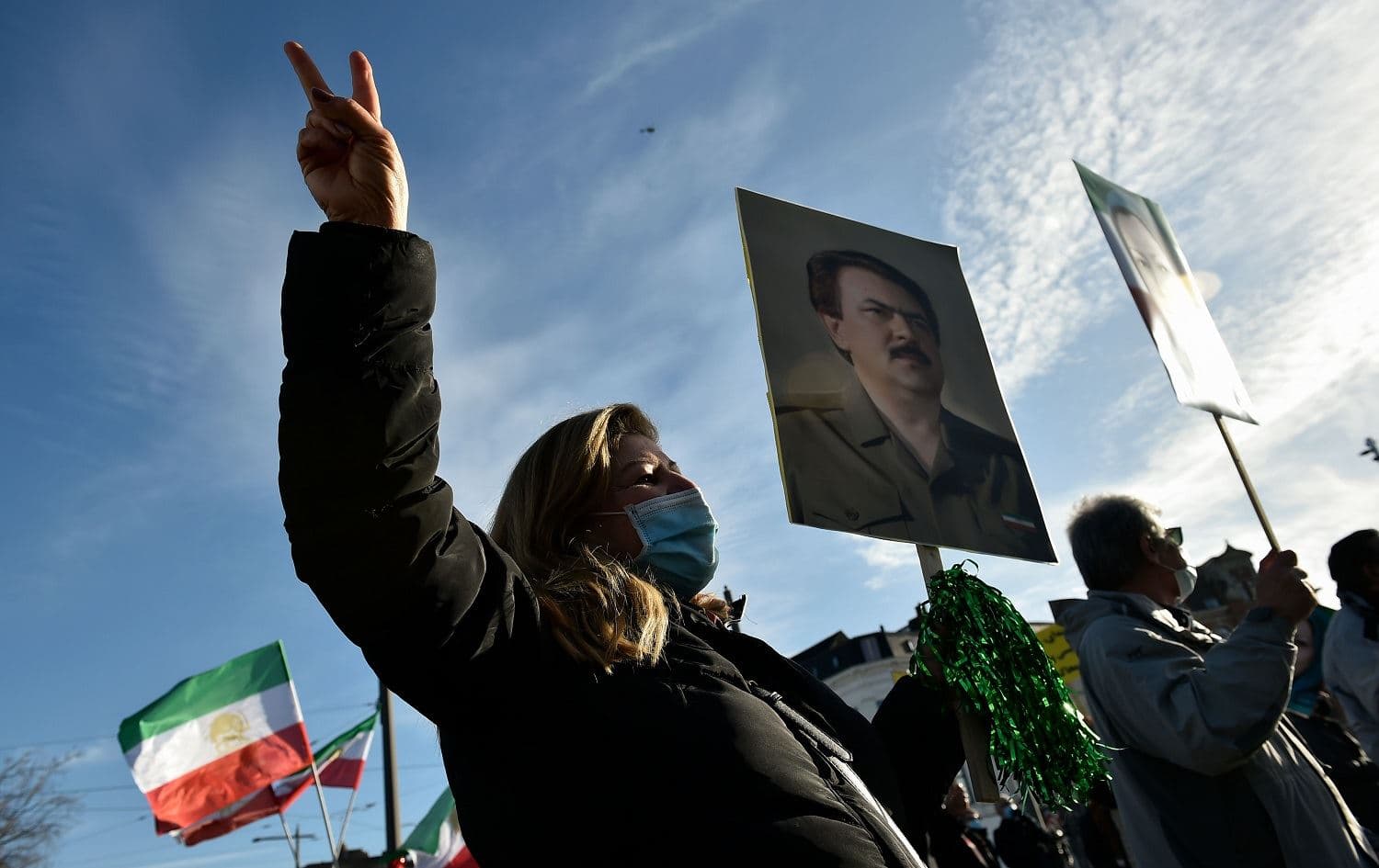People wave former flags of Iran and hold portraits as they protest outside the Antwerp courthouse, on February 4, 2021, during the trial of four suspects including an Iranian diplomat accused of taking part in a plot to bomb an opposition rally in France. Photo: John Thys/AFP