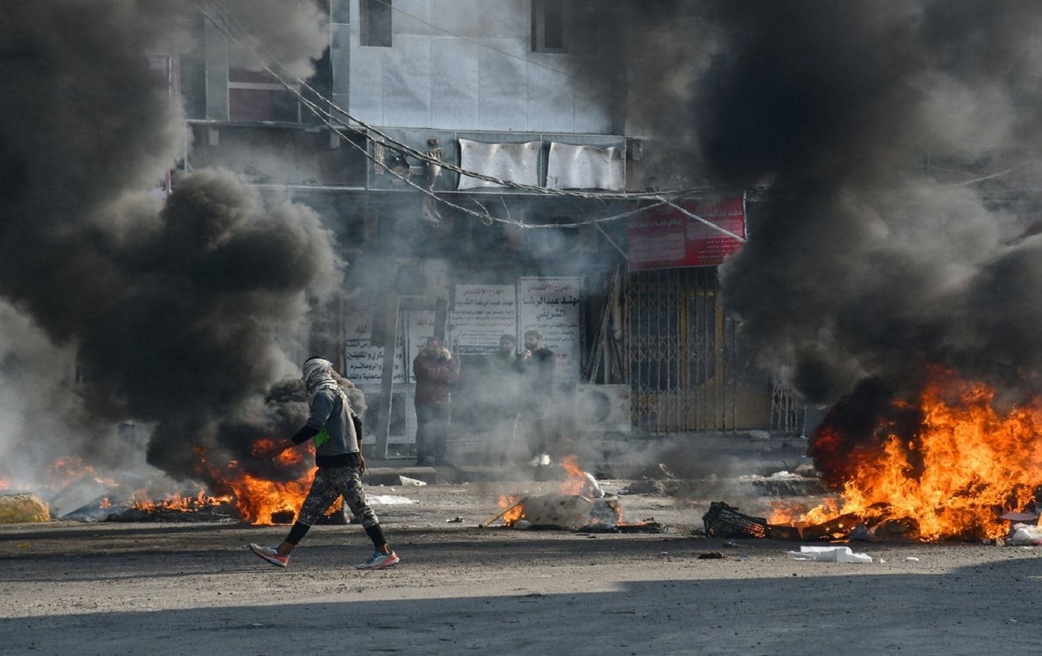 An man walks past burning tires during clashes with police in Nasiriyah on January 10, 2021. Photo: AFP