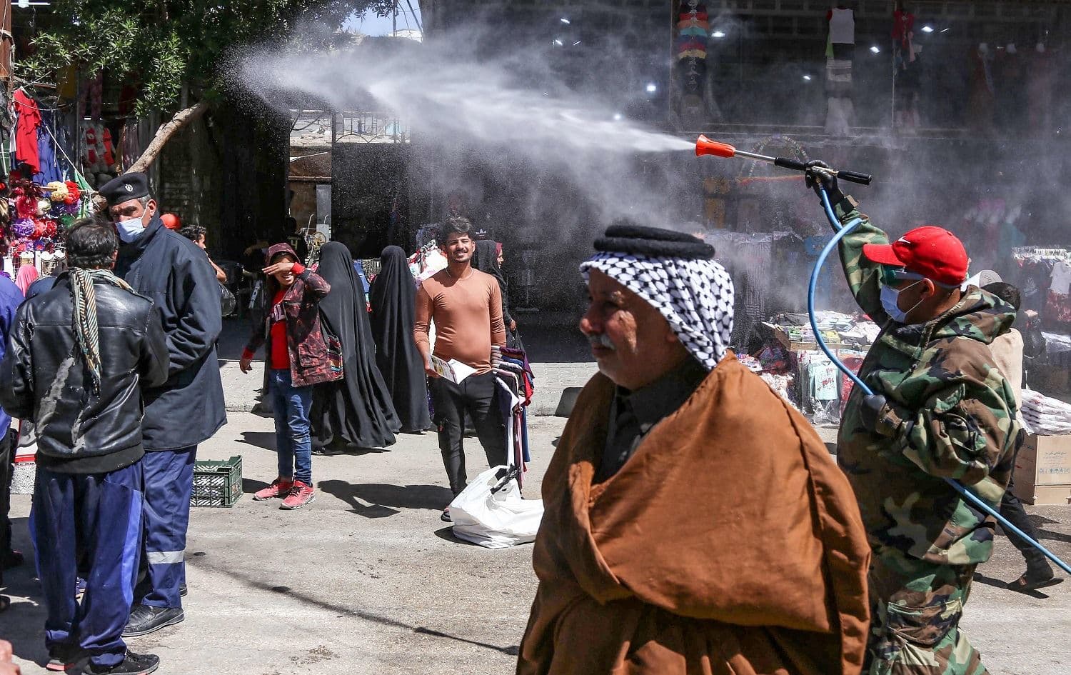 A member of the Iraqi security forces sprays disinfectant in a busy Karbala street on March 28, 2021, ahead of festivities marking the birth of Imam al-Mahdi,revered by Shiites as the coming Messiah. Photo: Mohammed Sawaf/AFP