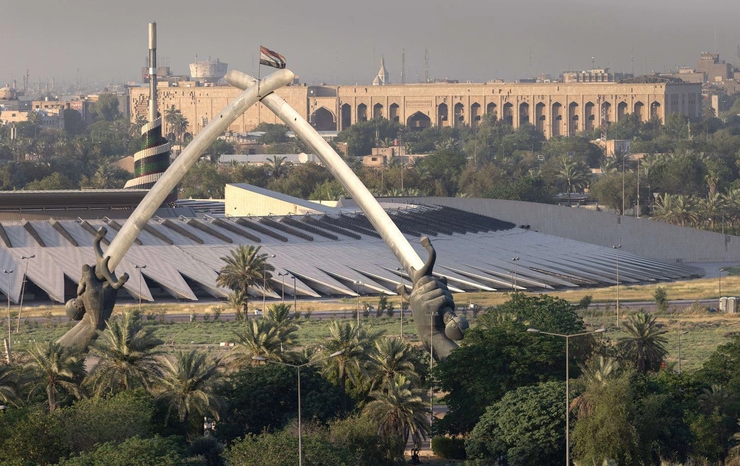The Crossed Sabers monument and the Iraqi Tomb of the Unknown Soldier stand near a Saddam-era statue as seen from the International Zone on May 29, 2021 in Baghdad. Photo: John Moore/Getty Images/AFP
