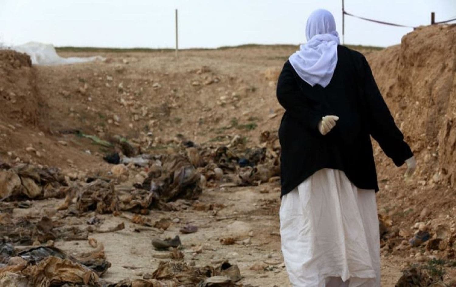A Yazidi woman stands next to a mass grave in Shingal. File photo: Safin Hamed/AFP