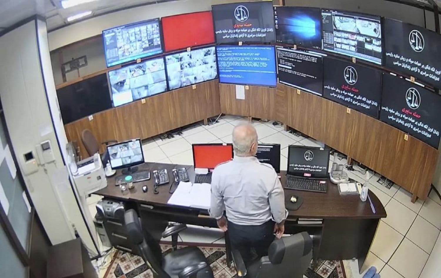 In this undated frame grab taken from video shared with AP by a self-identified hacker group called "The Justice of Ali," a guard looks at surveillance screens taken over by the group, at Evin prison in Tehran, Iran.
