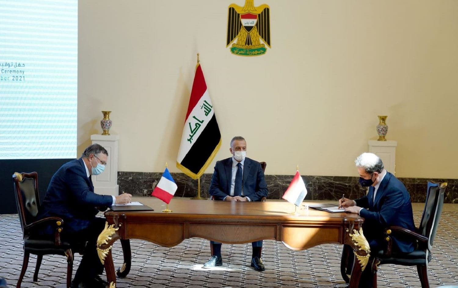 Iraqi Prime Minister Mustafa al-Kadhimi (centre) looks on as TotalEnergies CEO Patrick Pouyanne (left) and Iraqi Oil Minister Ihsan Abdul-Jabbar Ismael (right) sign a contract in Baghdad on September 5, 2021. Photo: handout/PM office