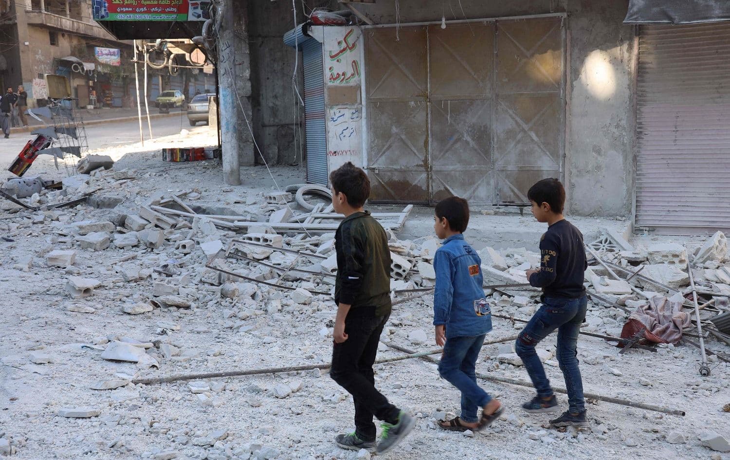 Children walk past debris at the site of shelling in the Syrian town of Ariha in the rebel-held northwestern Syrian Idlib province on October 20, 2021. Photo: Mohammed al-Rifai/AFP