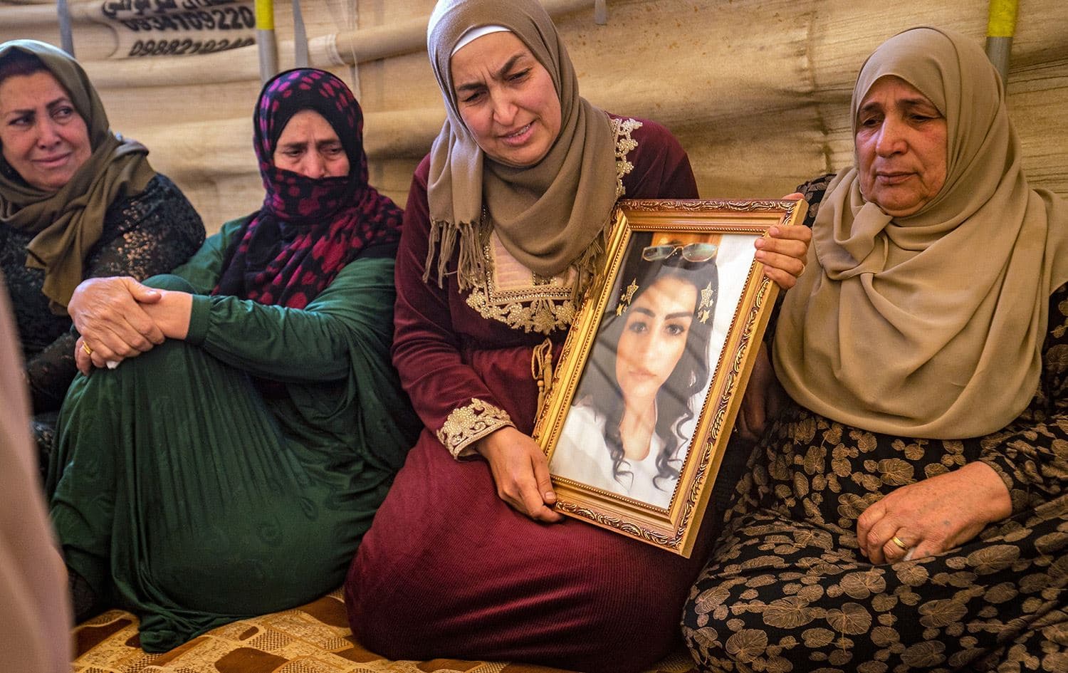 Hiam Saadoun holds a framed photograph of her daughter Inas Abdel Salam (23) at a tent during a memorial service for the missing woman in Syria's northeastern city of Qamishli on May 4, 2022. Photo: Delil Souleiman/AFP