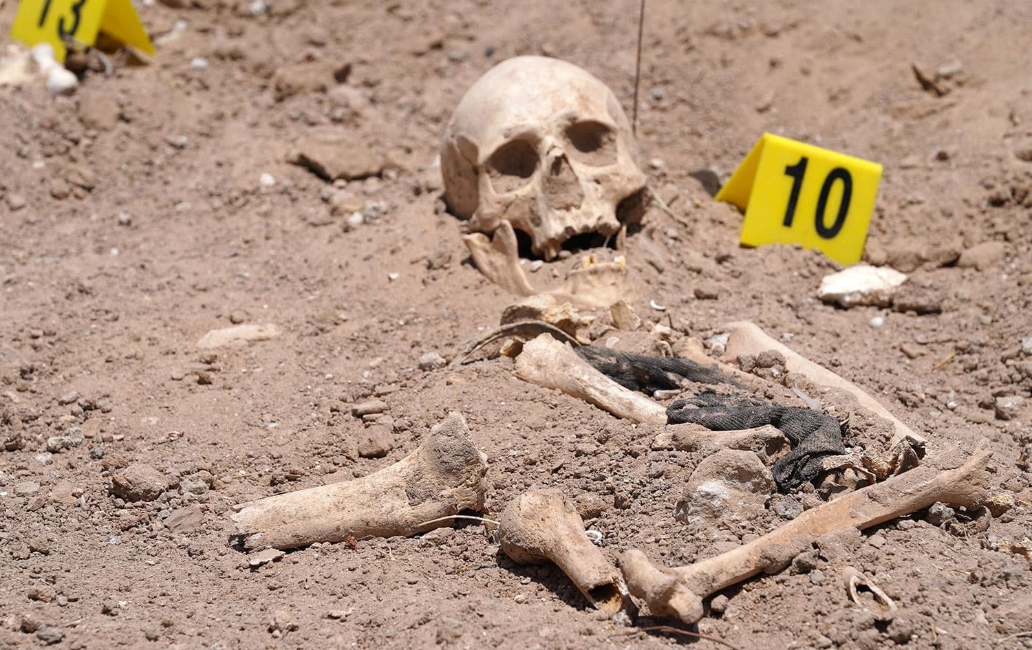 Human remains exhumed from a mass grave by Iraqi authorities, lie on the ground near the southern city of Najaf, on May 14, 2022. Photo: AFP