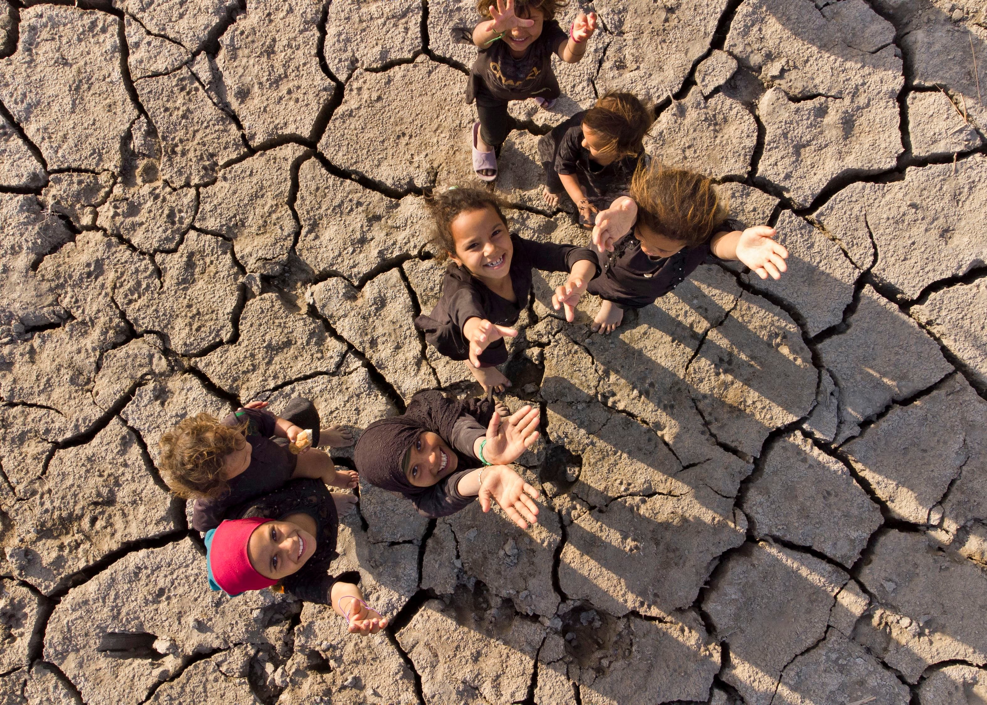 Children posing on the dried-up bed of Iraq's southern marshes of Chibayish in Dhi Qar province on August 23, 2022. Photo: Hussein Faleh/AFP