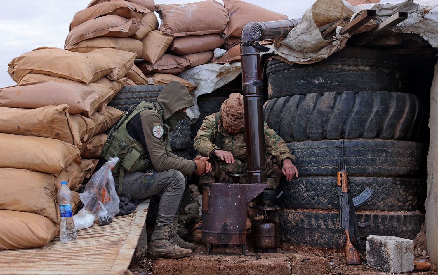 Fighters of the third corps of the Turkish-backed "Syrian National Army" warm up by sandbags and truck tires along a make-shift fortified position near Azaz in the rebel-held north of the Aleppo province on November 29, 2022. Photo: Aaref Watad/AFP