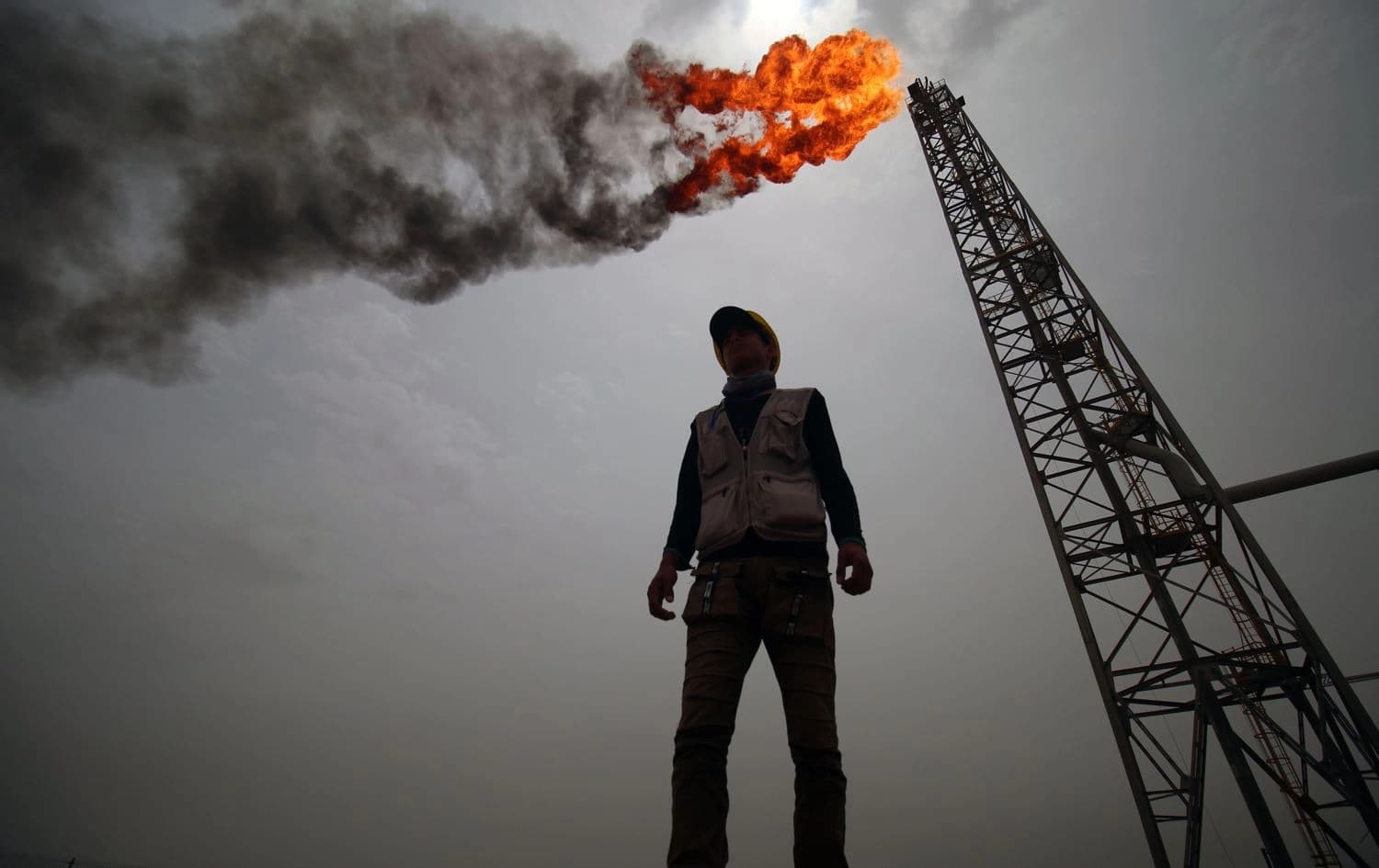 An oil worker stands in front of a derrick in Iraq. Photo: Haidar Mohammed/AFP
