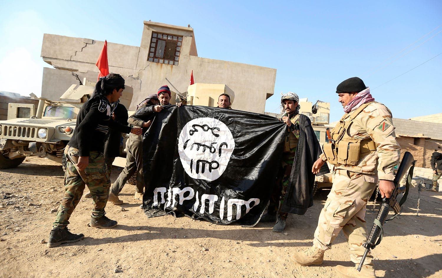 Iraqi army soldiers celebrate as they hold an ISIS flag they captured during a military operation to regain control of a village outside Mosul on November 29, 2016. Photo: Hadi Mizban/AP