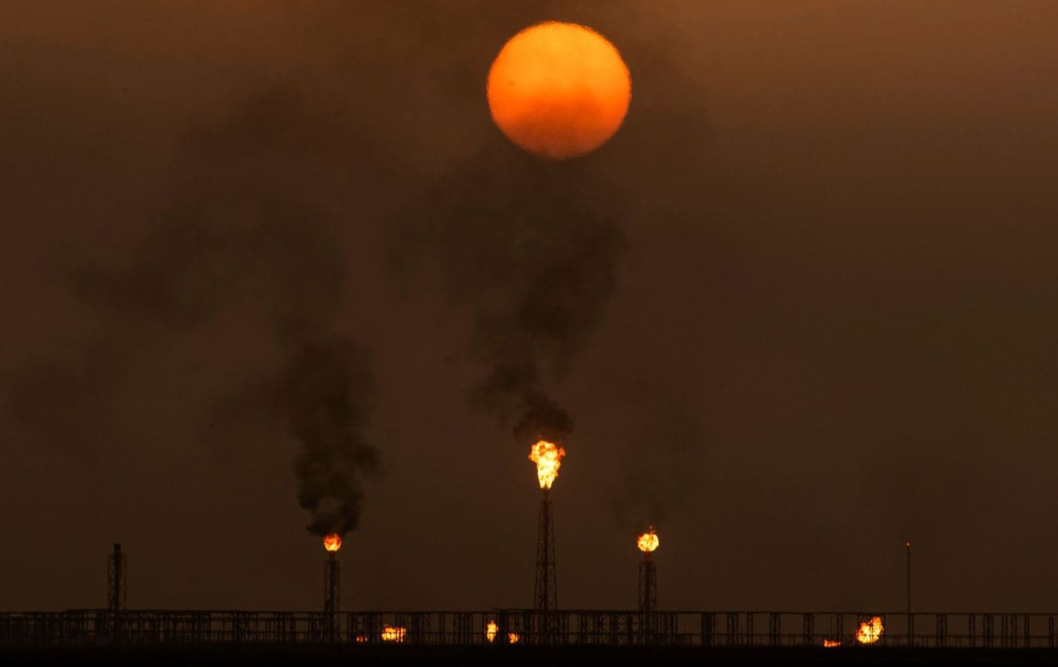 The sun sets as flare stacks burn off excess gas at the Mushrif site inside the Zubair oil and gas field, north of the southern Iraqi province of Basra, on July 13, 2022. Photo: Hussein Faleh/AFP