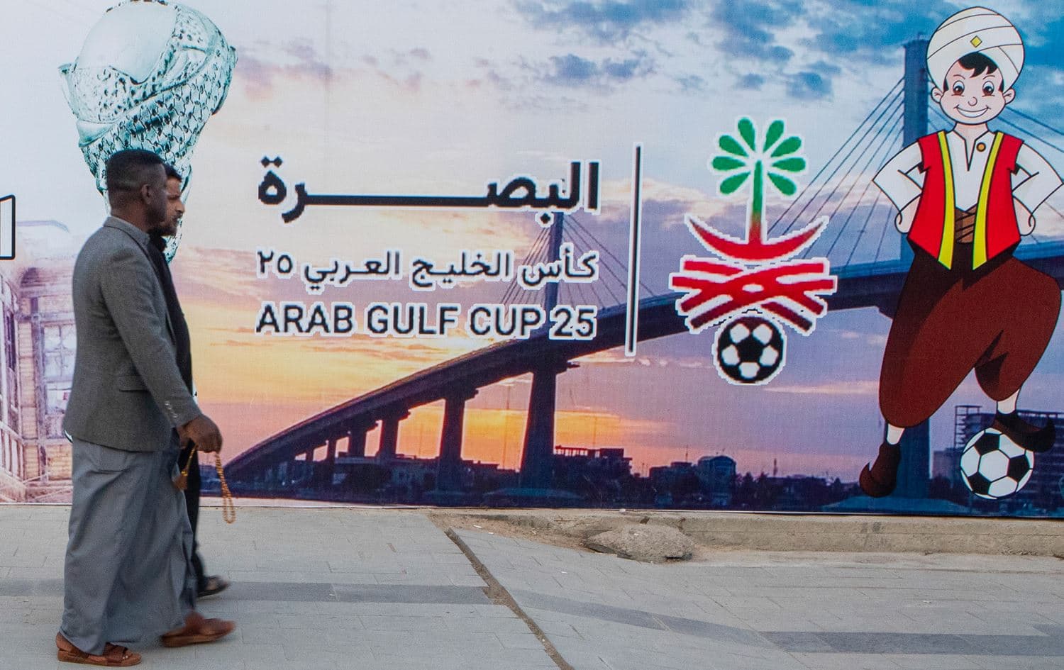 People pass by a billboard announcing 25th Arab Gulf Cup in Basra on January 3, 2023. Photo: AP/Nabil al-Jurani