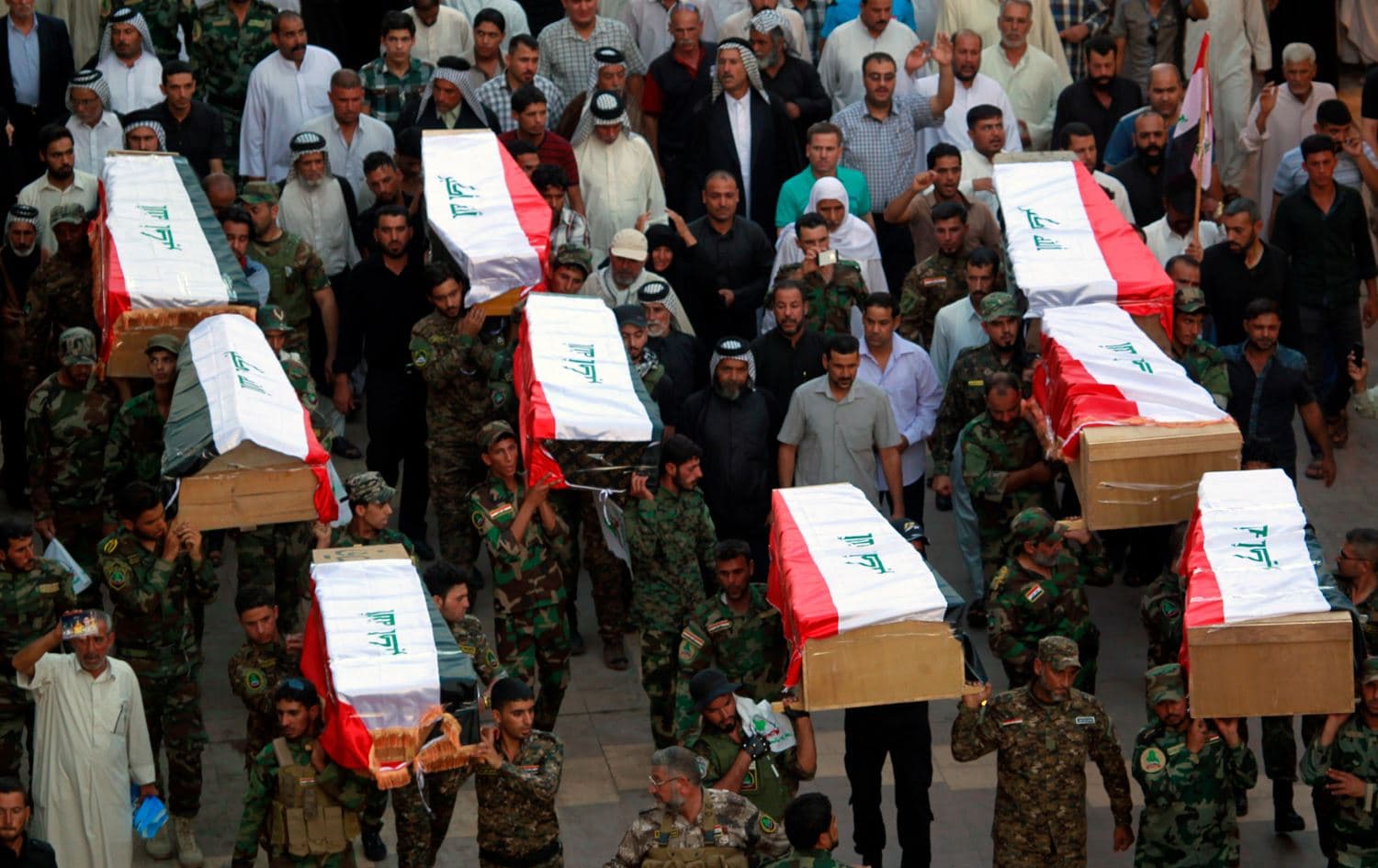 Iraqi soldiers carry coffins containing the remains of ten of their comrades killed in the Camp Speicher massacre, during a funeral procession in the holy Iraqi city of Najaf. Photo: AFP