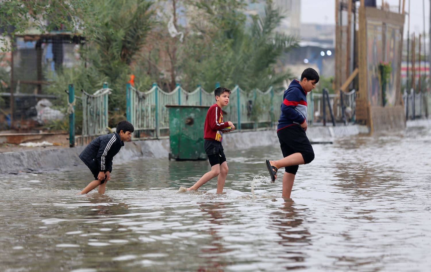 Iraqi children cross a flooded street in the capital Baghdad on December 24, 2022. Photo: AFP