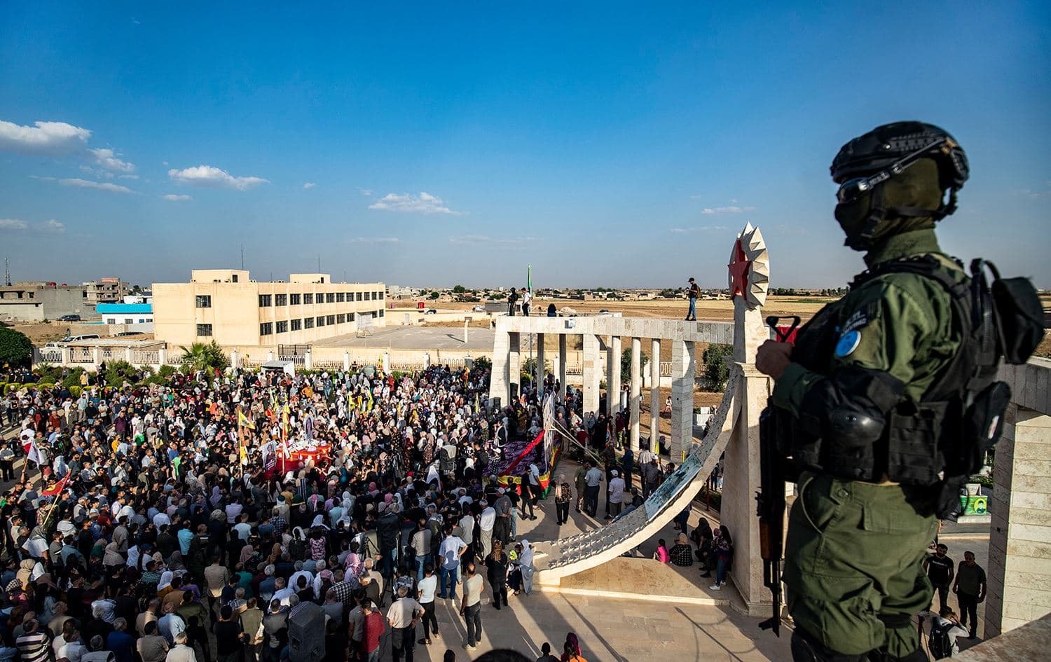 A member of the Syrian Kurdish Asayish security forces stands guard as mourners carry the coffins of two Kurdish women killed a day earlier in a reported Turkish drone strike, during their funeral in Amuda, a town in the Hasakah governorate in northeastern Syria, on June 21, 2023. Photo: Delil Souleiman/AFP