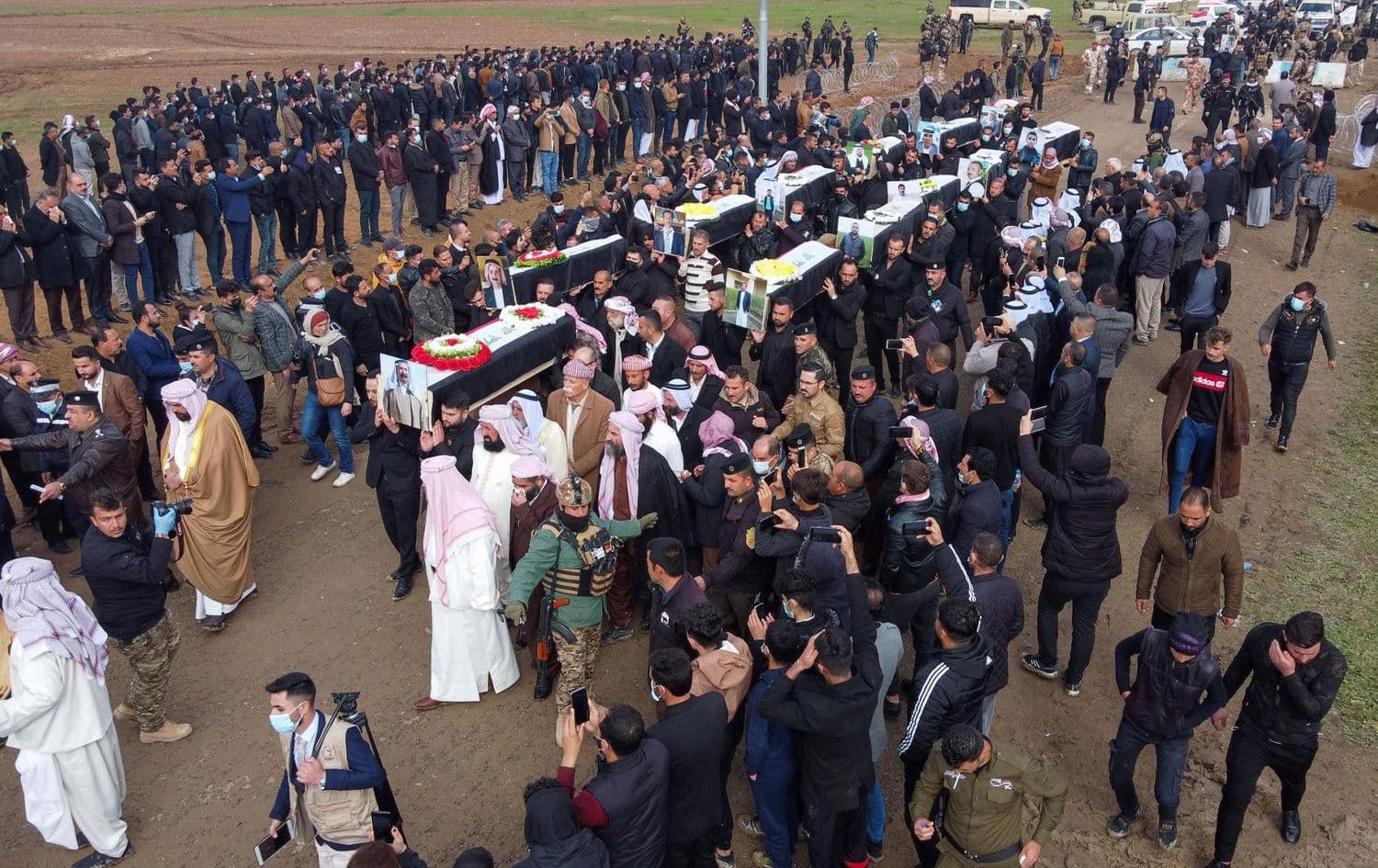 Mourners carry coffins wrapped in the Iraqi flag during a mass funeral for victims of the Yazidi genocide in the village of Kocho in Shingal. Photo: AFP