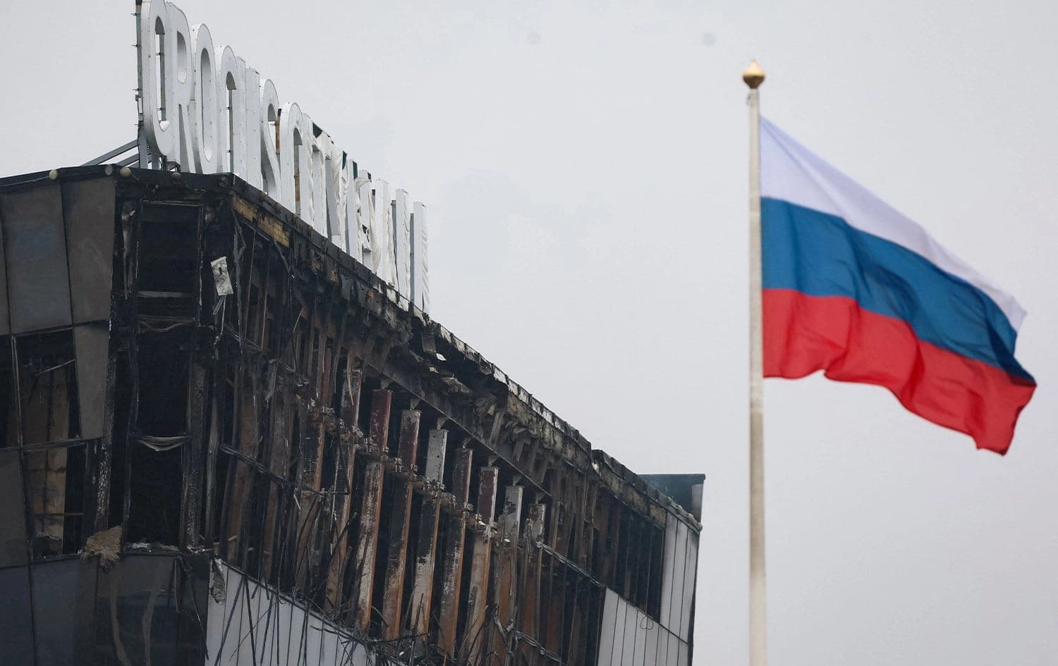 A Russian national tricolor flag flutters in the wind near the burned Crocus City Hall concert hall, the scene of the gun attack, in Krasnogorsk, outside Moscow, on March 23, 2024. Photo: STRINGER/AFP