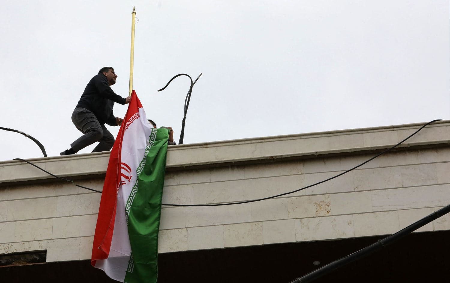 A staff member sets up the Iranian flag atop a new consular annex to Iran's embassy in Damascus on its inauguration day on April 8, 2024. Photo: LOUAI BESHARA / AFP
