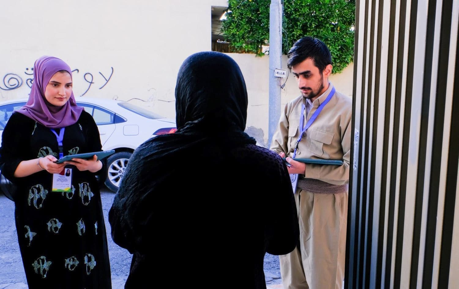 تیمێکی سەرژمێری لەبەردەم ماڵێکدا پرسیار لە ژنێک دەکەن.