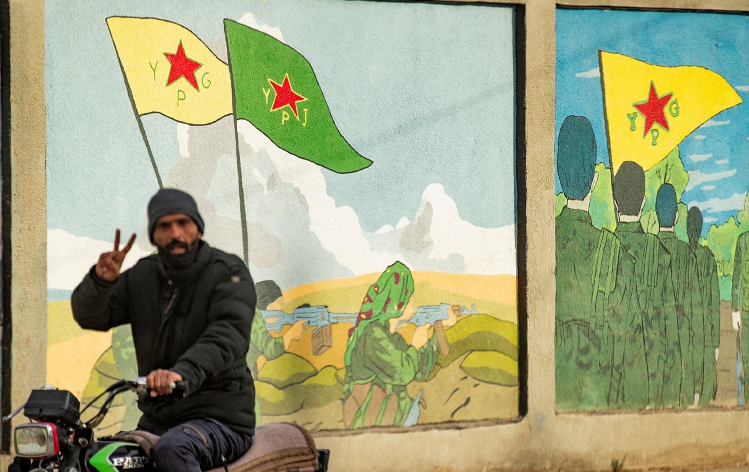 Wêneyê ala û şervanên YPGyê li Qamişloyê li ser dîwêr hatiye xêzkirin / AFP