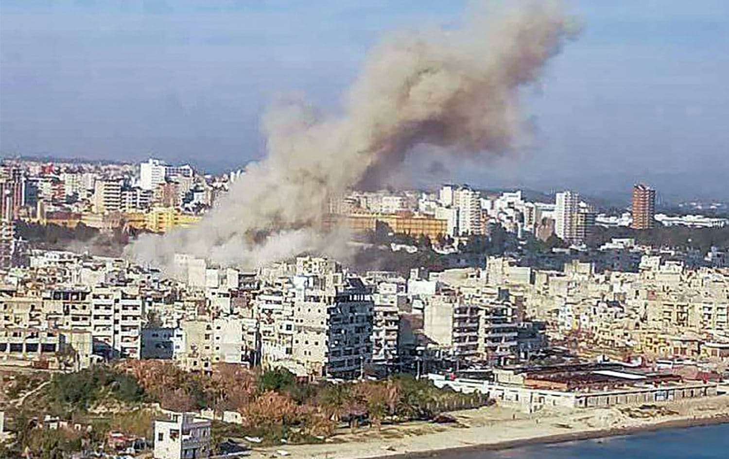 بەهۆی شەڕ و پێکدادان دووکەڵ لە باڵەخانەیەکی لازقیە بەرز دەبێتەوە. وێنە: AFP