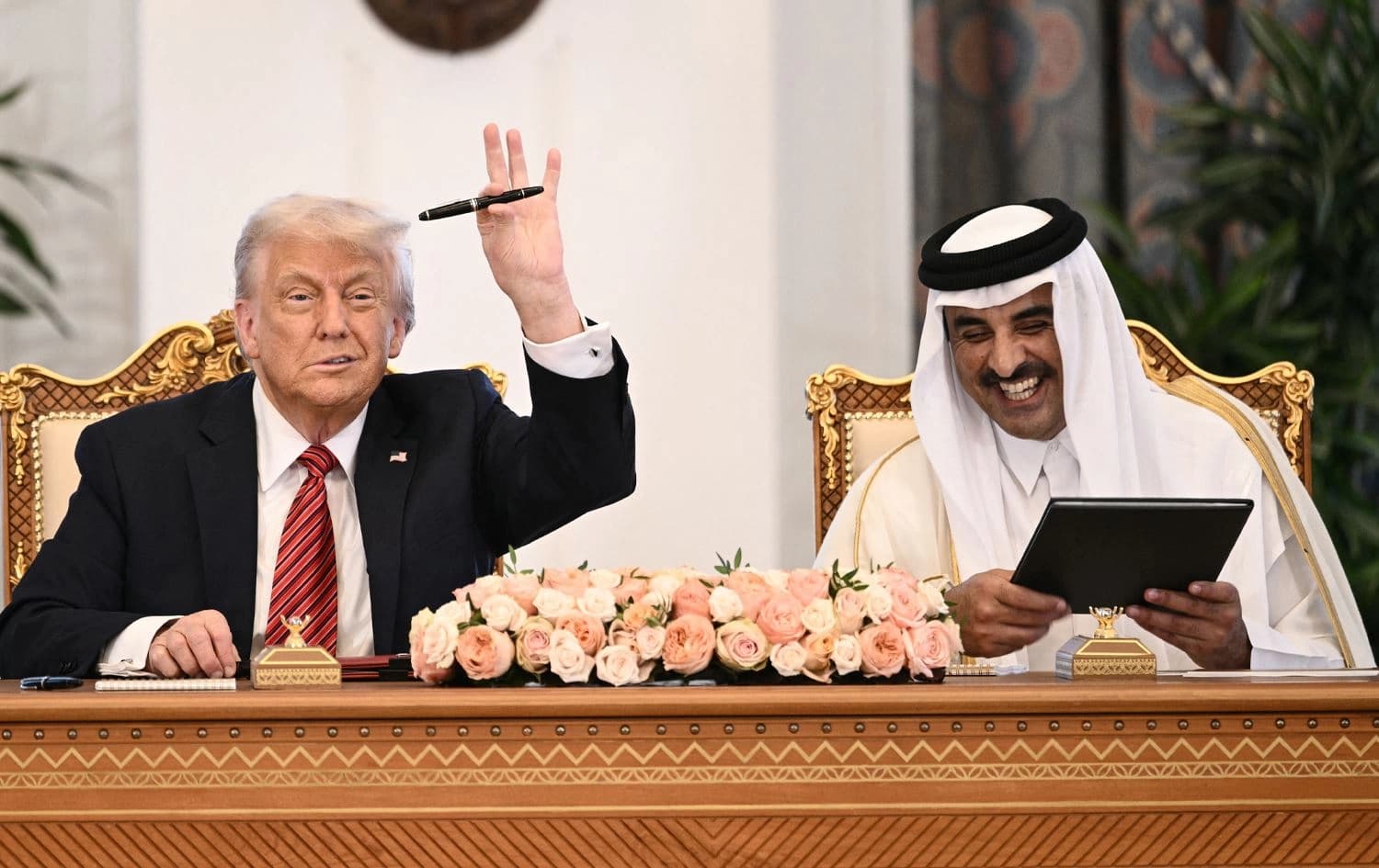دۆناڵد ترەمپ لەکاتی واژۆکردنی رێککەوتنەکە قەڵەمەکە بەرزدەکاتەوە. وێنە: AFP