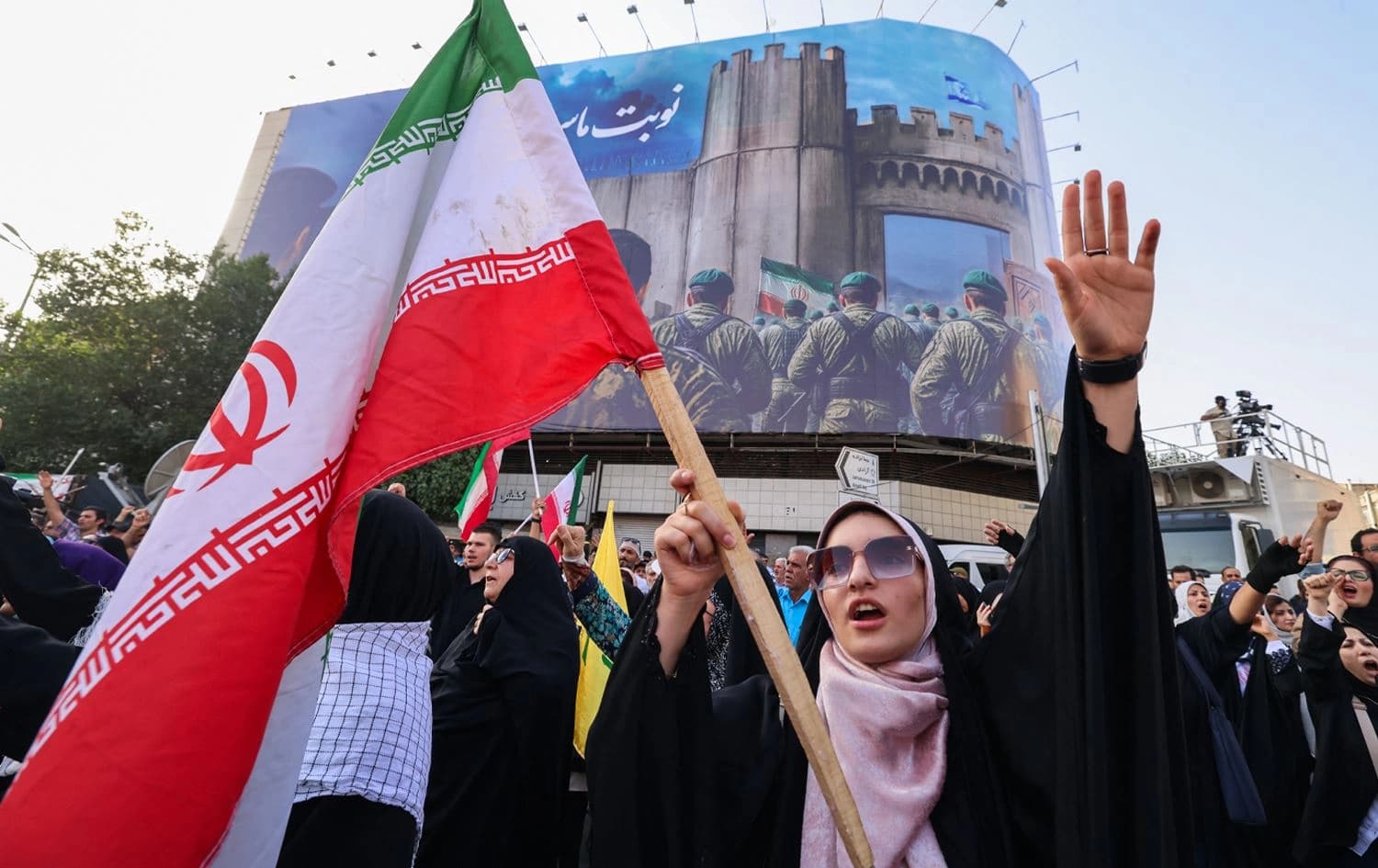 خۆپێشاندەرێک لە تاران ئاڵای ئێرانی بەرز کردووەتەوە. وێنە: AFP