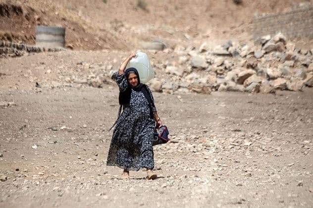 ژنێک لە پیرانشار کە دەبە ئاوی خستووەتە سەر شانی. وێنە: ئاژانسی تەسنیم