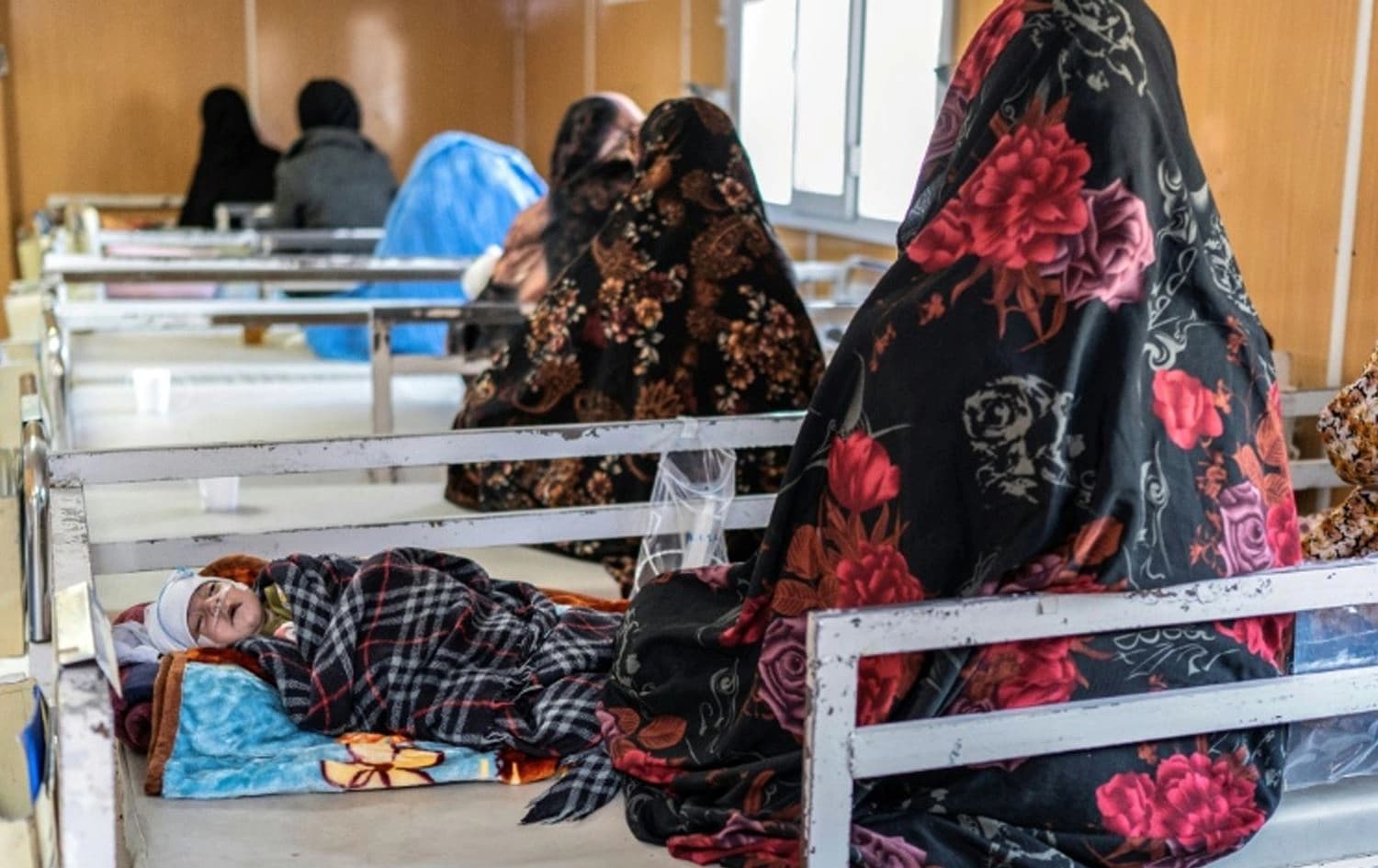چەند منداڵێک لەگەڵ دایکیان لەسەر تەختی نەخۆشانەیەکی ئەفغانستانن. وێنە: barrons