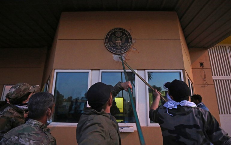 Protesters pull off a plaque from the entrance of the U.S. embassy in Baghdad on Dec. 31, 2019. Photo via AFP/Ahmad al-Rubaye