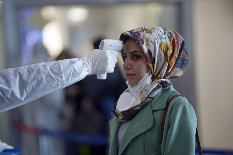 An Iraqi passenger returning from Iran has her temperature checked upon arrival at Najaf International Airport, March 5, 2020. Photo: Haidar Hamdani / AFP 