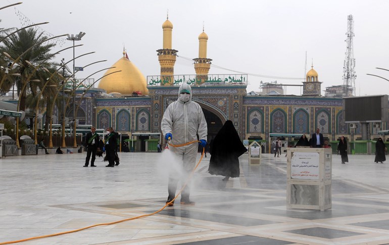 Iraqi health workers disinfect the area around the Imam Hussein Shrine (background) in Karbala on March 15, 2020. Photo: Mohammed Sawaf/ AFP