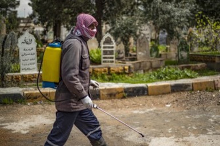 Worker disinfecting a graveyard in Qamishli. Photo: AFP