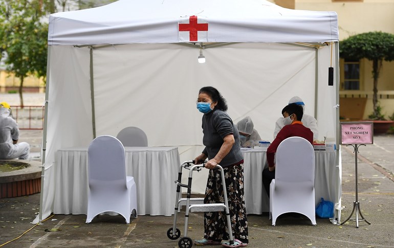 A woman, wearing a face mask as a preventive measure against the spread of the COVID-19 coronavirus, walks past a makeshift rapid testing centre near the Bach Mai hospital in Hanoi on March 31, 2020. Photo: Nhac Nguyen / AFP