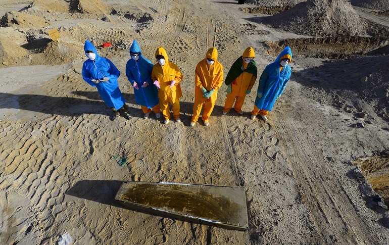  Iraqis in hazmat gear pray over the coffin of a victim of the COVID-19 virus before her burial 20 kilometers from the central holy city of Najaf on April 3, 2020. Photo: Haidar Hamdani / AFP
