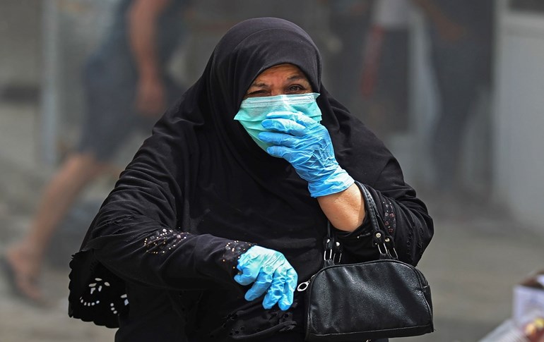 An Iraqi woman wearing protective gloves and a mask walks through Baghdad's Washash district, April 6, 2020. Photo: Ahmad al-Rubaye / AFP