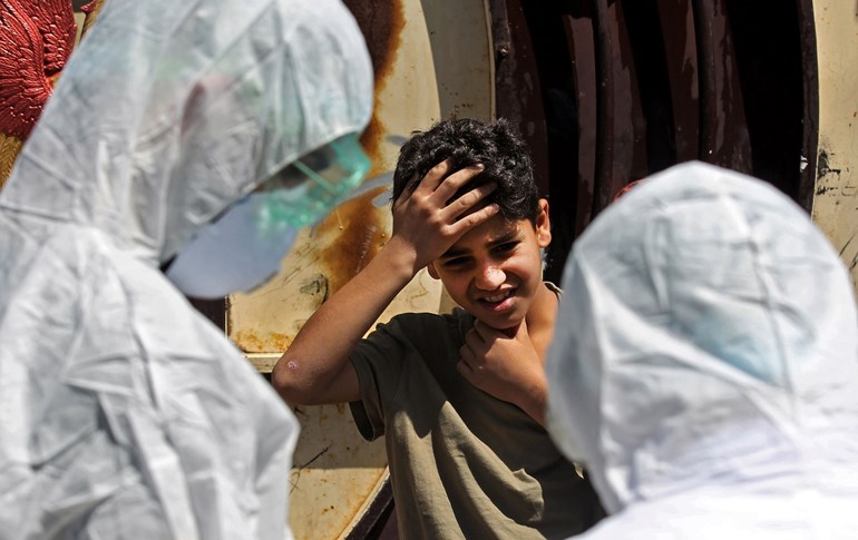  Iraqi doctors speak to a young boy before testing him for COVID-19 in Sadr City on April 2, 2020. Photo: Ahmad al-Rubaye/AFP