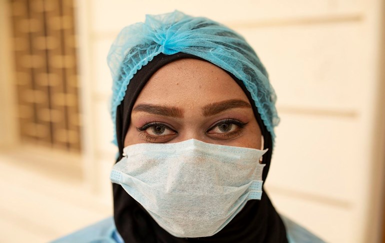 An Iraqi medic wearing a face mask and covering her headscarf with a protective cap poses for a photo at Basra University Hospital, where COVID-19 coronavirus patients are treated, in the southern Iraqi city of the same name on April 1, 2020. Photo: Hussein Faleh/ AFP