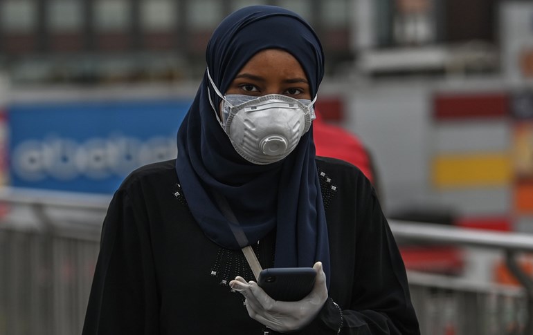 A woman wearing two face masks and gloves walks on a bridge near a bus station in Istanbul on April 15, 2020. Photo: Ozan Kose/AFP