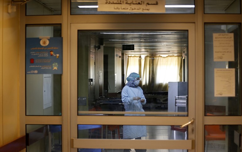  A worker at Al-Assad University Hospital in Damascus stands behind the entrance door of a special department designated for COVID-19 testing on April 15, 2020. Photo: Louai Beshara/AFP