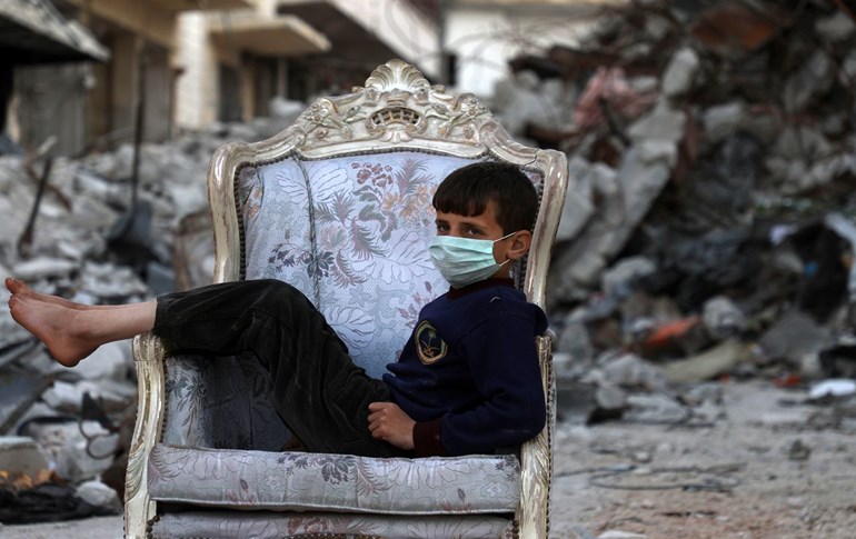 A child sits on a couch found in a street, ravaged by pro-regime forces air strikes, in the town of Ariha in the southern countryside of the Idlib province on April 11, 2020. Photo: Aaref Watad/ AFP