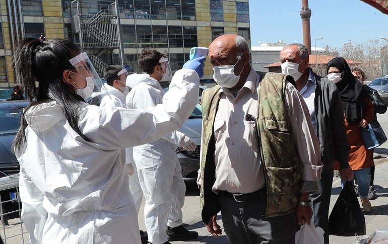 A health official checks a man's body temperature at the covered bazaar in the historic Ulus district, Ankara on April 17, 2020. Photo: Adem Altan / AFP