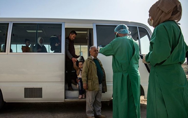 Health workers prepare to check passengers arriving to northeast Syria from the Kurdistan Region for symptoms of the coronavirus on Feb. 26, 2020. Photo: Delil Souleiman/AFP