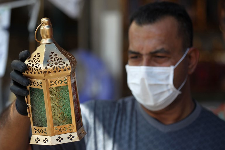 An Iraqi man wearing plastic gloves and a protective mask holds a traditional lantern known in Arabic as "Fanous" at the Shorja market in central Baghdad on April 21, 2020. Photo: Ahmad Al-Rubaye/ AFP